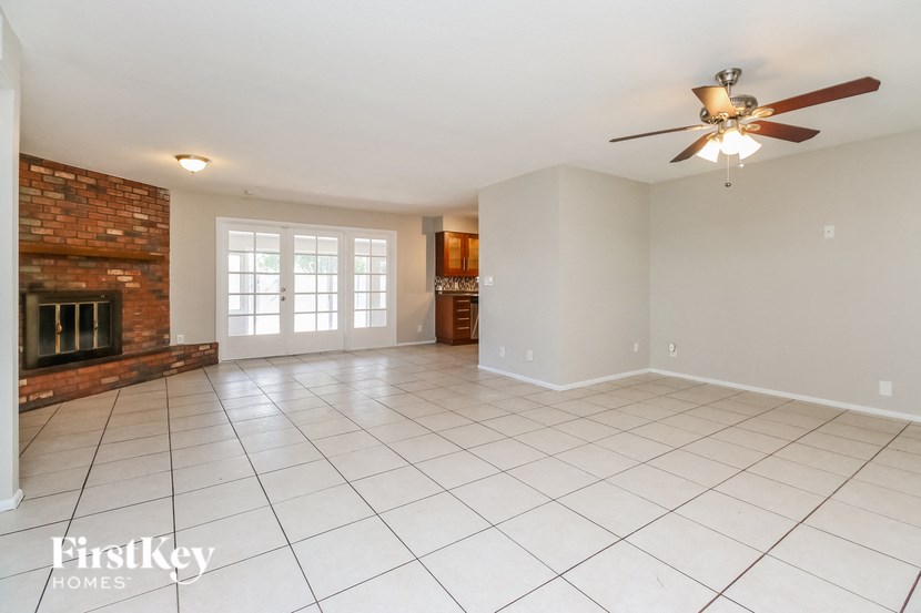 an empty living room with a fireplace and a ceiling fan