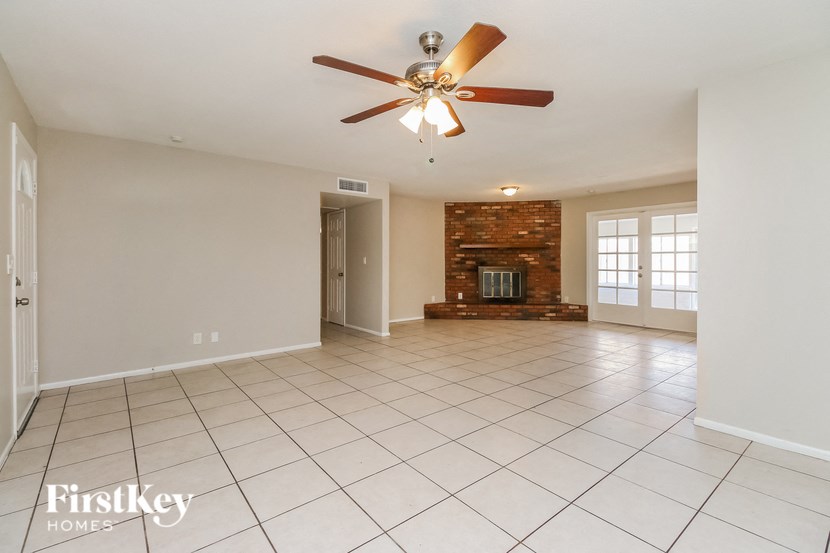an empty living room with a ceiling fan and a fireplace