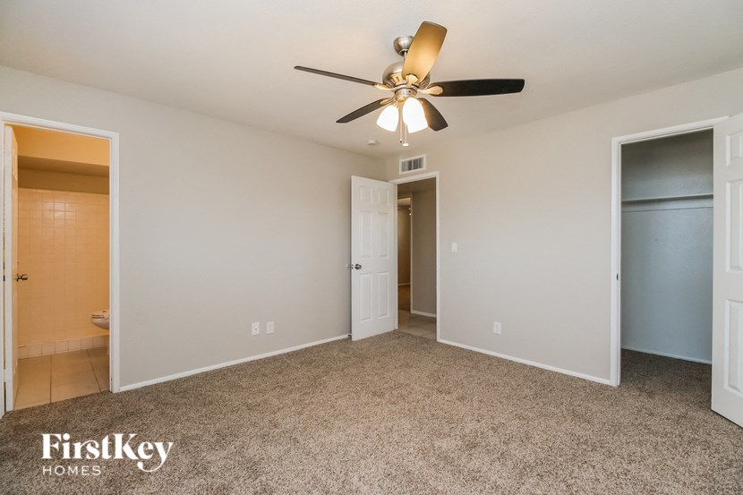 a bedroom with a ceiling fan and a door to a closet