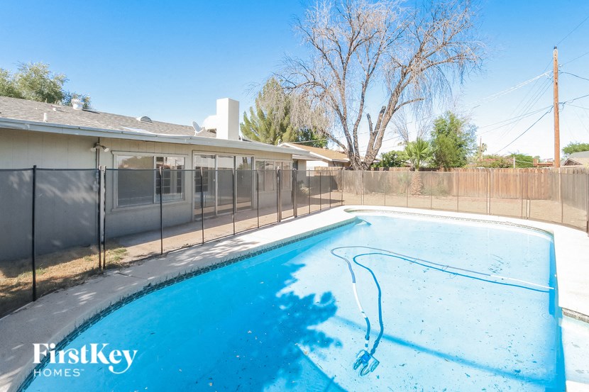 a pool with a fence and a house in the background