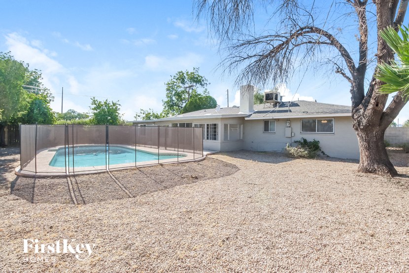 a yard with a pool and a house with a fence