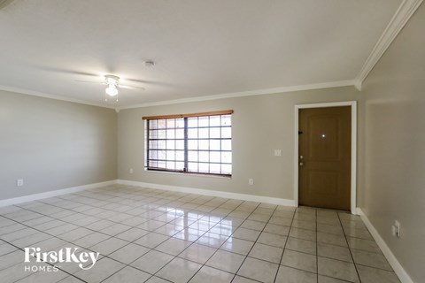 an empty living room with tiled floors and a window