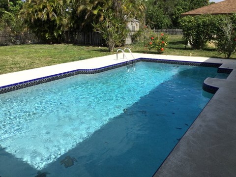 A small rectangular pool with a white coping and a blue tiled border.