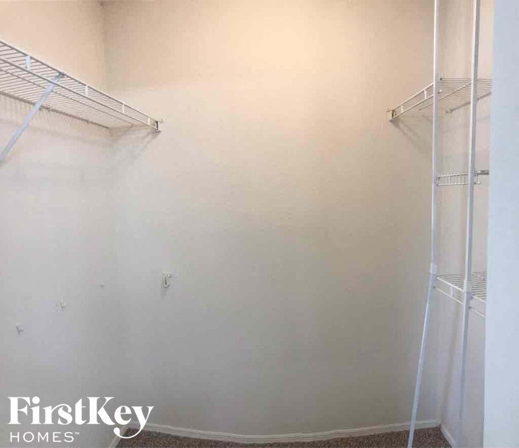 a walk in closet in a room with white walls and shelves