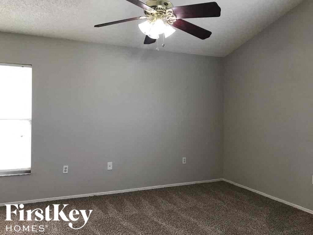 a empty room with a ceiling fan and a gray wall