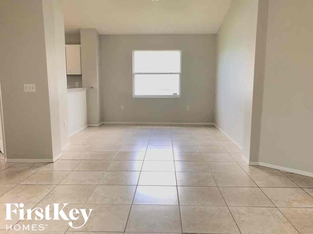 an empty living room with tiled floors and a window