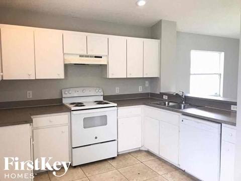 an empty kitchen with white appliances and white cabinets