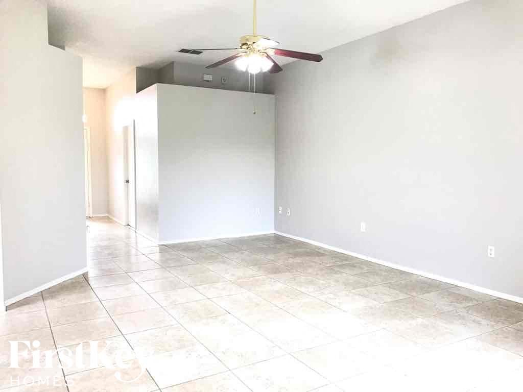 an empty living room with white walls and a ceiling fan