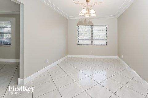 an empty dining room with white tile flooring and a window