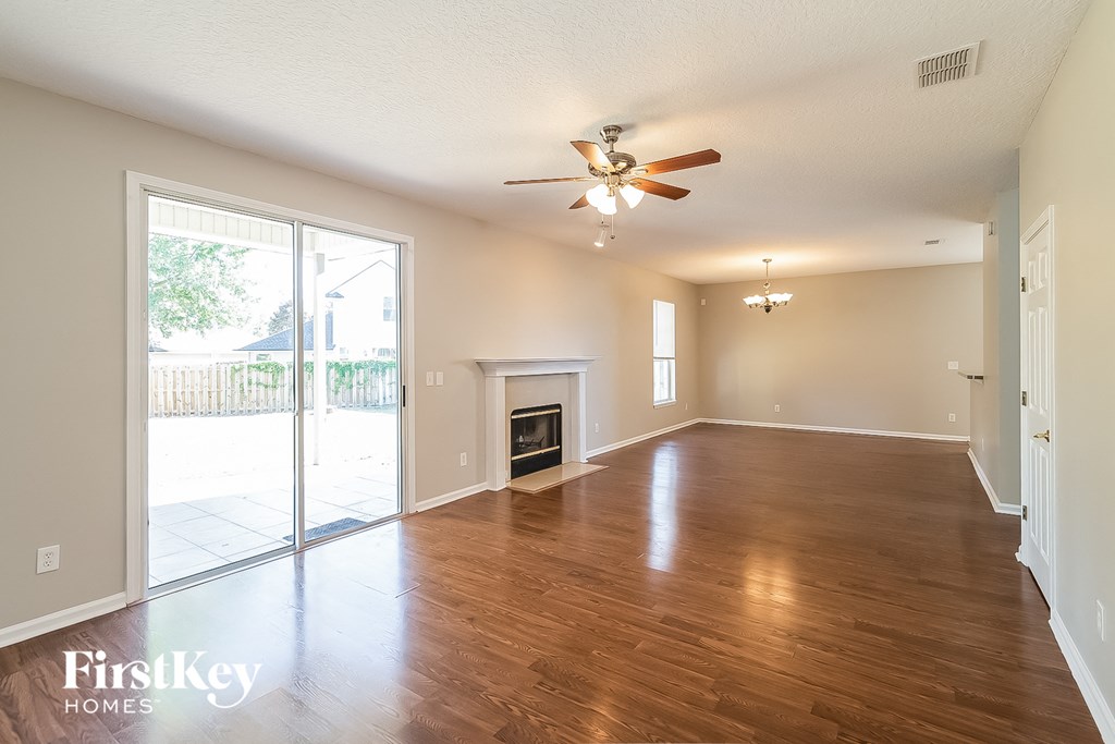an empty living room with a fireplace and a ceiling fan