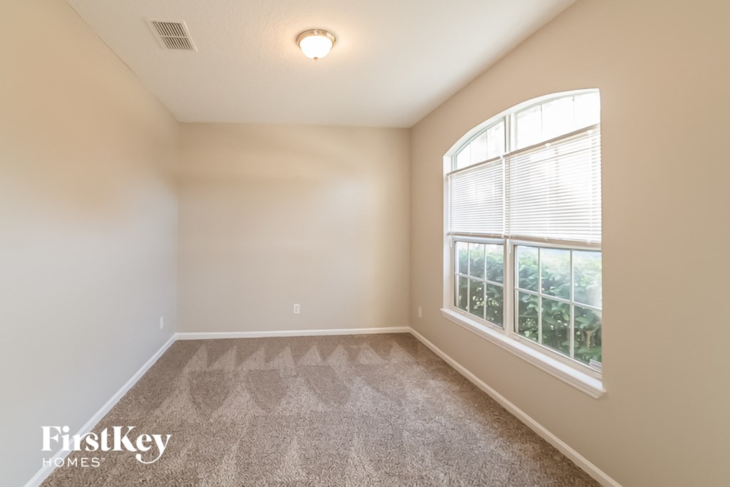 a bedroom with a large window and carpeted flooring