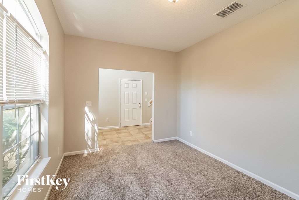 a living room with a carpeted floor and a door to a hallway