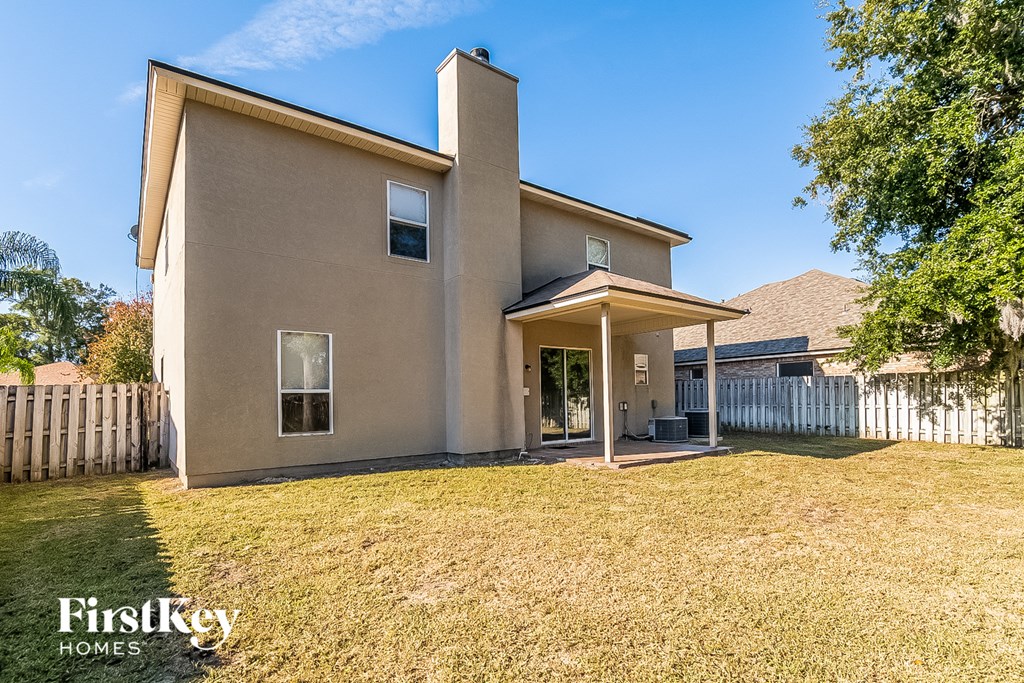 a beige house with a yard and a white fence