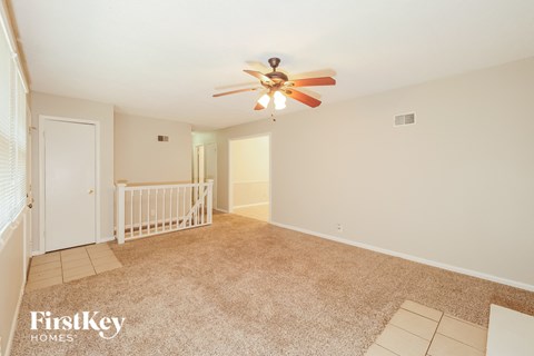 A spacious room with a fan and a baby gate.