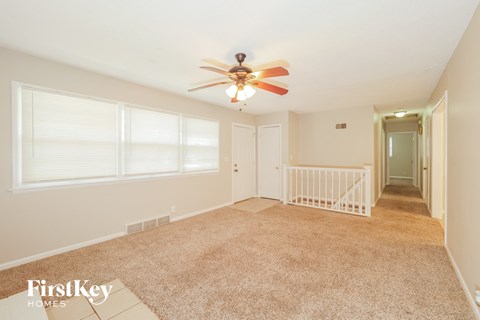 A spacious room with a fan and carpeted floor.
