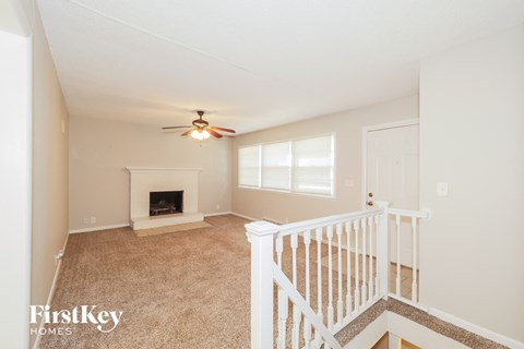 A living room with a fireplace and a fan on the ceiling.