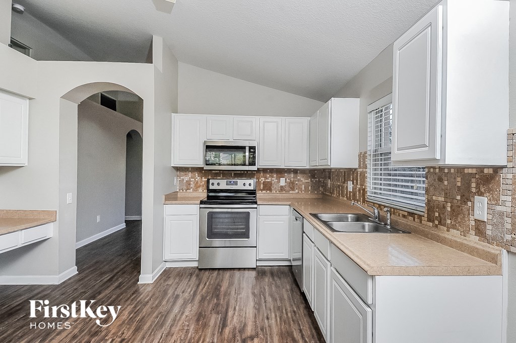a kitchen with white cabinets and a sink and an oven