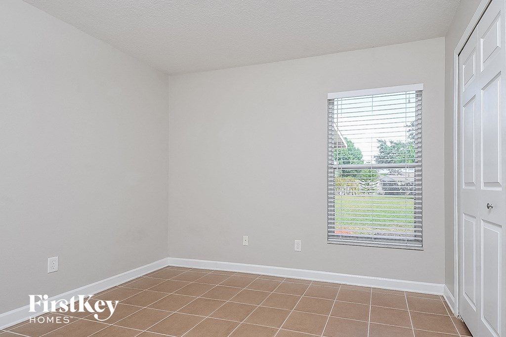 a bedroom with a window and a tiled floor