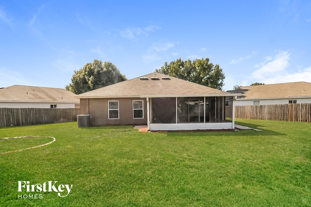 a backyard with a bungalow with a grass yard and a house with glass
