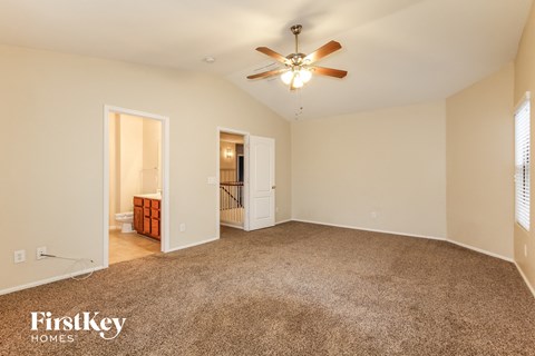 a spacious living room with carpet and a ceiling fan