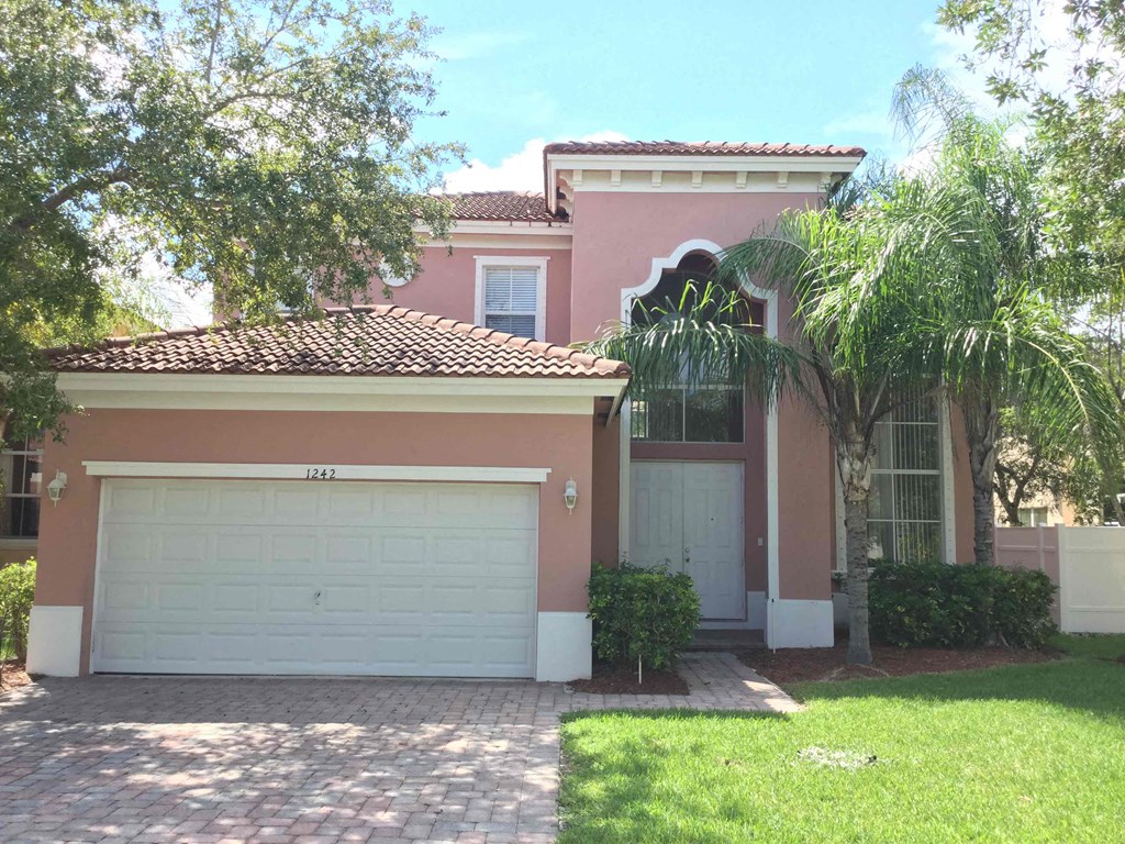 a pink house with a garage door and a palm tree