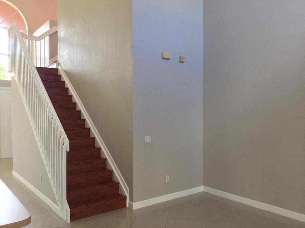 a view of the staircase in a house with white walls and a wooden stairwell