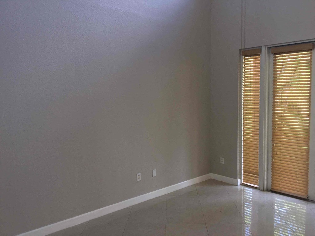 an empty living room with two windows and a tiled floor