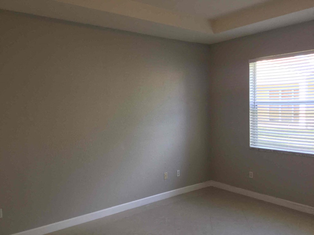 an empty room with a window and gray walls
