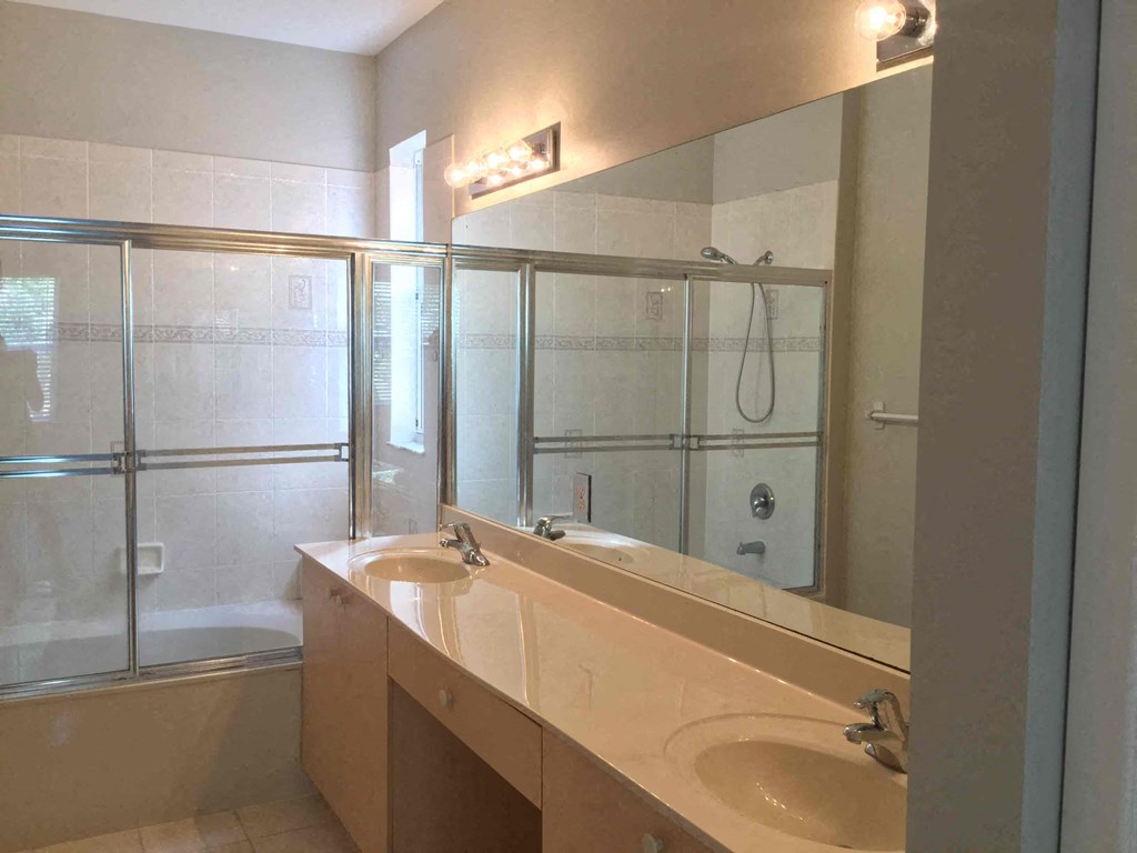 a bathroom with two sinks and a shower and a mirror