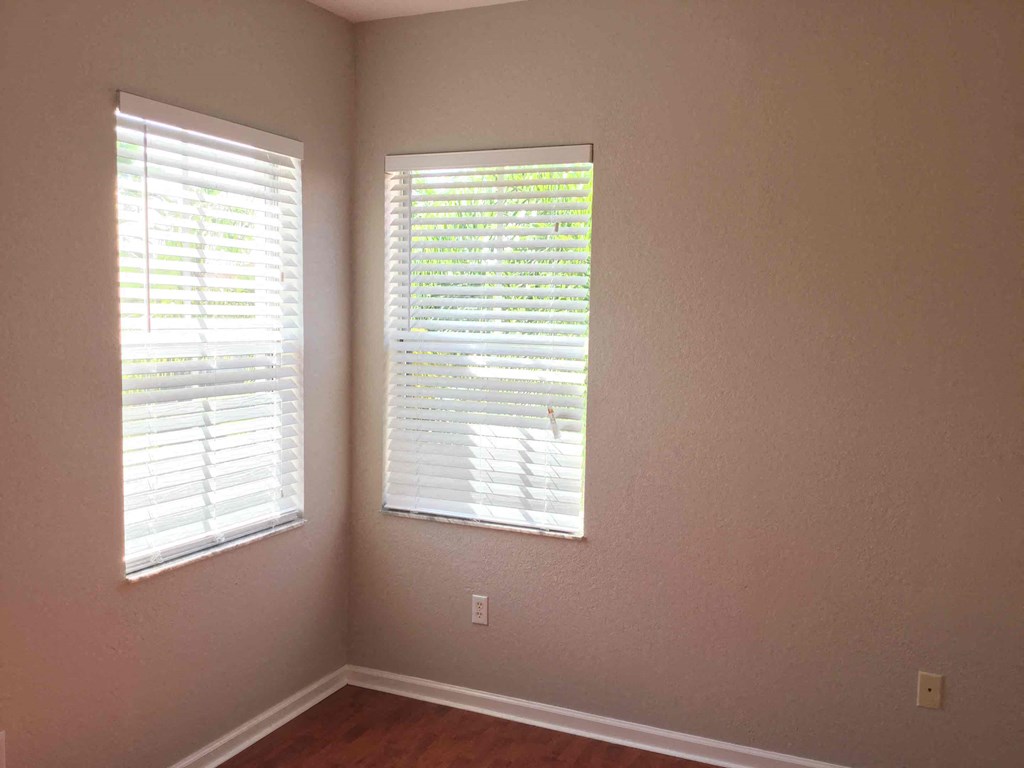 a room with two windows with white blinds