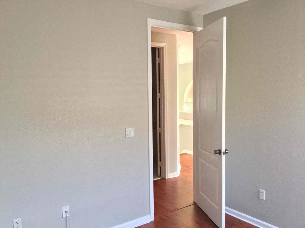 an empty room with a door open and a hallway to a closet