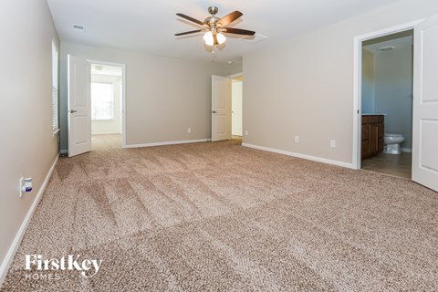 a spacious living room with carpet and a ceiling fan