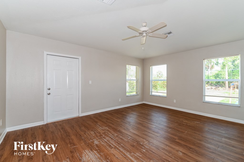 an empty living room with wood floors and a ceiling fan