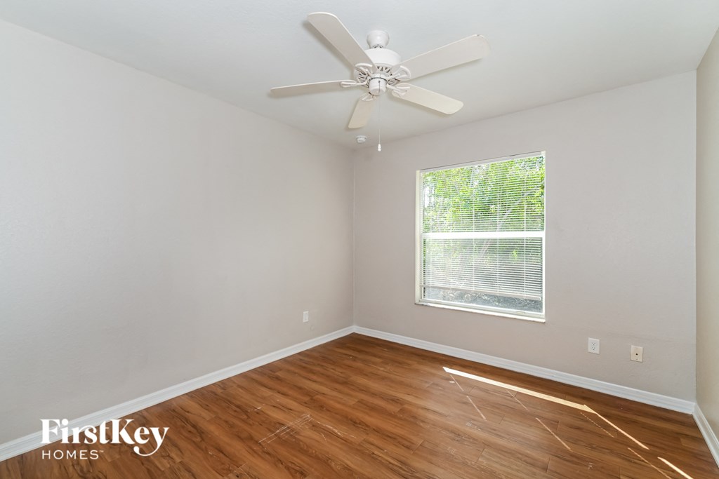 a bedroom with hardwood flooring and a ceiling fan