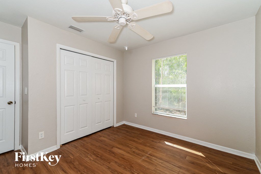 a bedroom with a white door and a ceiling fan