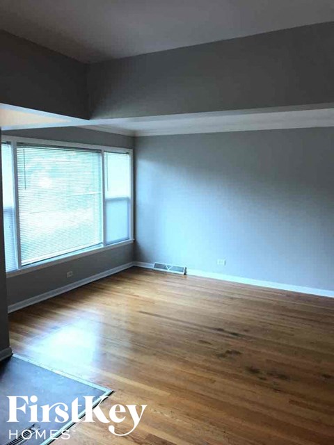 an empty living room with wood floors and a large window