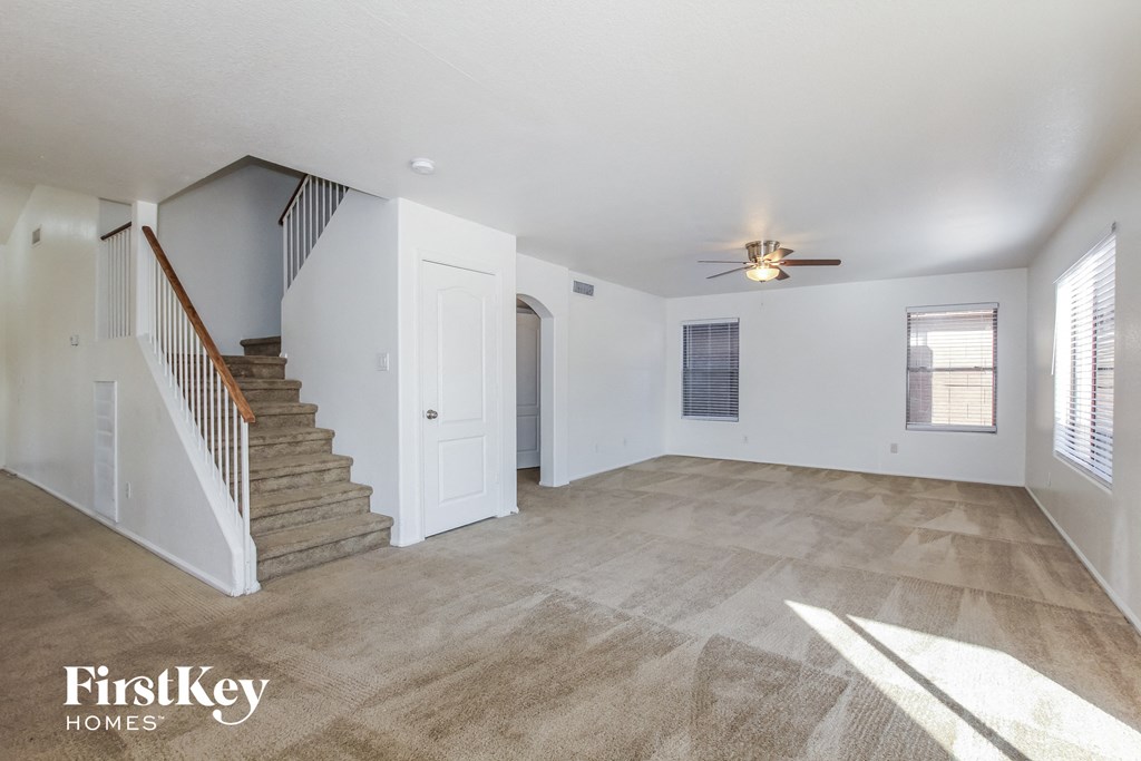 A spacious room with a staircase and a ceiling fan.
