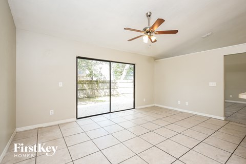 an empty living room with a ceiling fan and a sliding glass door