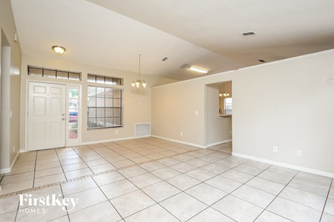 an empty living room with a white door and tiled floor
