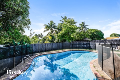 a resort style pool with a fence around it and palm trees