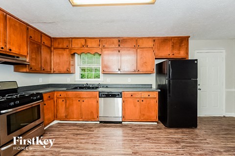 A kitchen with wooden cabinets and a black refrigerator.