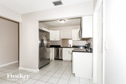 A kitchen with white cabinets and a stainless steel refrigerator.