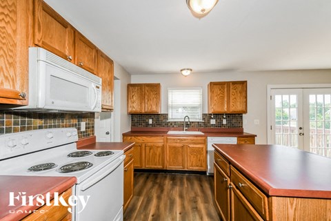 a kitchen with wooden cabinets and white appliances and a stove top oven