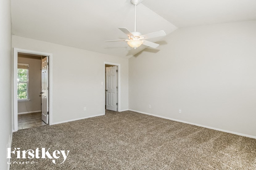 the spacious living room with white walls and a ceiling fan