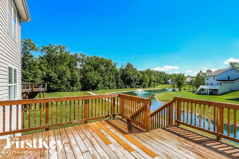 a deck overlooking a body of water with a pond and a house