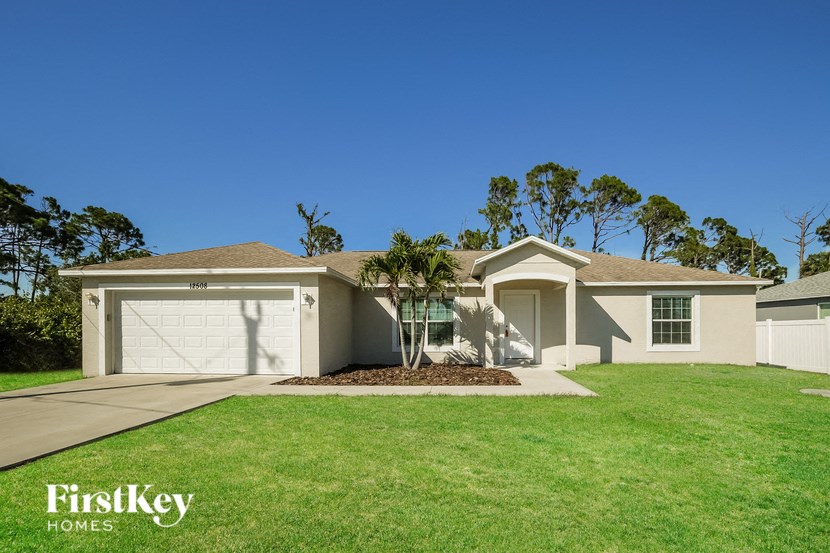A house with a garage and a tree in front of it.
