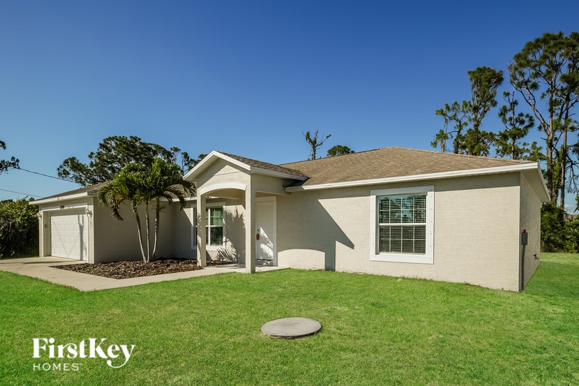 A house with a lawn and a tree in front of it.