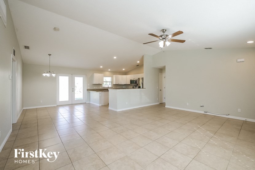 A spacious living room with a ceiling fan and tiled flooring.