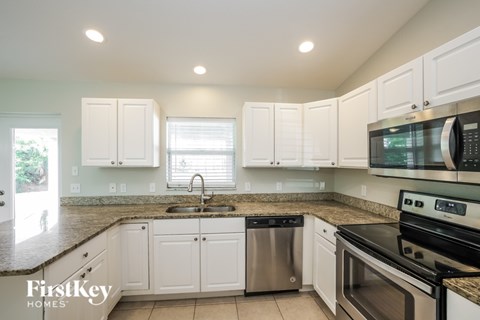 A kitchen with white cabinets and a black stove top oven.