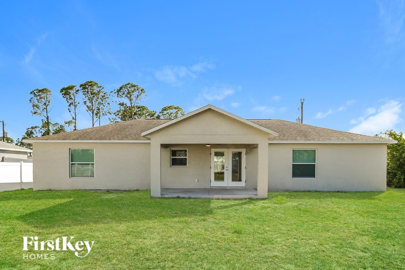 A house with a green lawn and trees in the background.